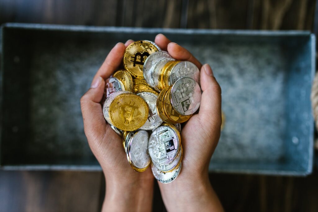 person holding gold and silver round coins
